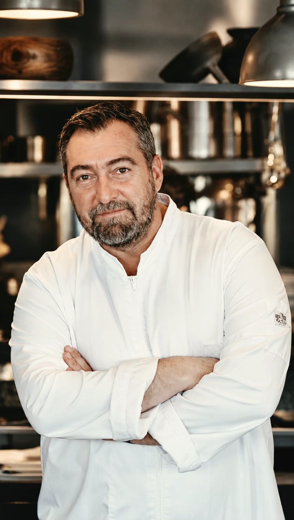 Portrait of chef Stefanos Kokkalis in a white chef jacket inside a professional kitchen